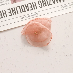 Macro-detail van een zachtroze organza stoffen bloem met een centraal kristallen kraal