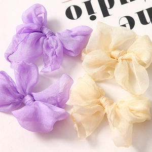 Dettaglio di delicati fiocchi in organza viola e beige per creazioni artigianali DIY