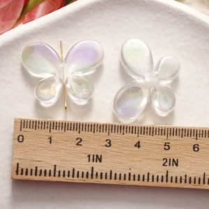 Macro detail of iridescent butterfly resin charms with golden pins and scale measurement