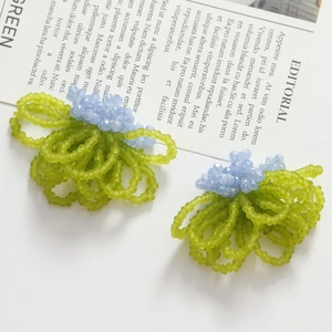 Detail of handmade beaded flower earrings featuring light green and blue glass beads