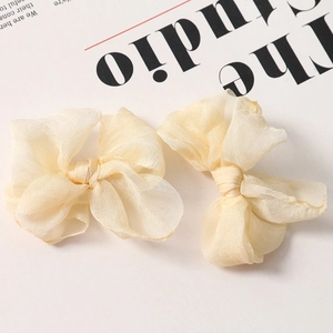 Dettaglio di eleganti fermagli per capelli a fiocco in organza crema con seta plissettata