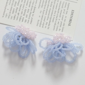 Detailed close-up of handmade beaded floral earrings in pastel pink and light blue tones