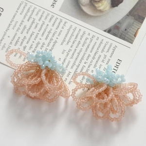 Macro detail of handmade woven glass bead flower earrings in pink and blue floral design