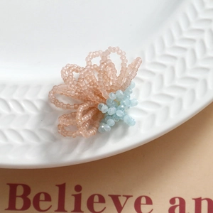 Macro shot of handmade woven flower bead accessory with pink petals and blue crystal center