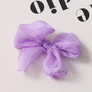 Dettaglio macro di un fiocco in organza viola con trama a rete e lucentezza soffusa