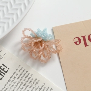 Close-up of handmade pink woven glass bead flower with light blue center for DIY jewelry