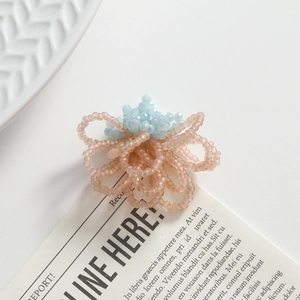 Detailed macro view of handmade pink and blue beaded floral earring on white tray