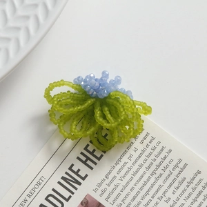 Macro detail of handmade woven glass flower bead jewelry with blue and green beads