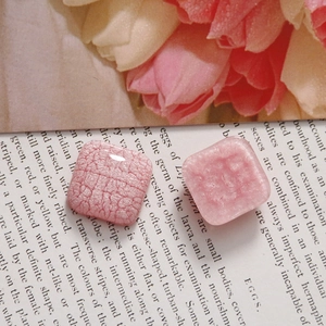 Détail de breloques carrées en résine rose avec effet de texture fumée et craquelée