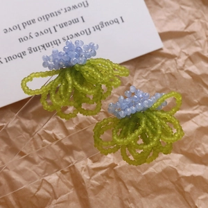 Handmade blue flower bead earrings with a summer forest theme on vintage paper