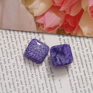 Vue macro de breloques carrées en résine violette avec texture craquelée pour bijoux DIY