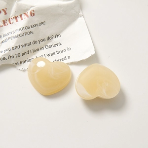 Detailed macro view of heart-shaped cream resin accessories with marble ink texture