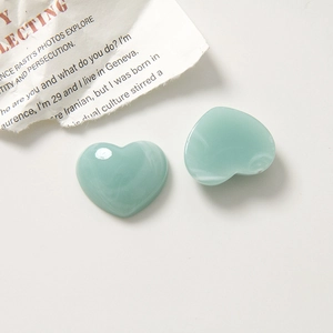Macro detail of two heart-shaped resin charms with mint green and white marble pattern