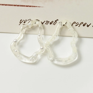 Primer plano de anillos de resina irregulares con perlas incrustadas en fondo neutro