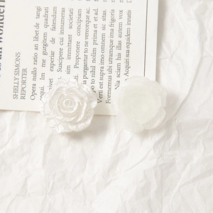 Detailed macro view of white acrylic rose charms with elegant crackle and matte finishes
