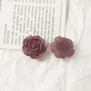 Detailed view of dark red acrylic rose charms with vintage cracked paint texture effect