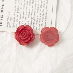 Close-up of red acrylic rose accessories with vintage distressed gold edges for DIY jewelry