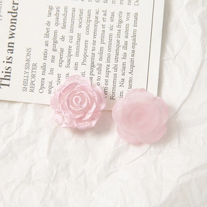 Macro detail of pink acrylic rose with crackle texture and matte floral DIY charms