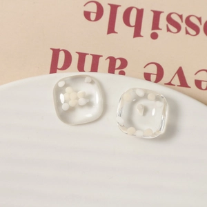 Macro-opname van minimalistische vierkante hars oorbellen met witte sferen erin