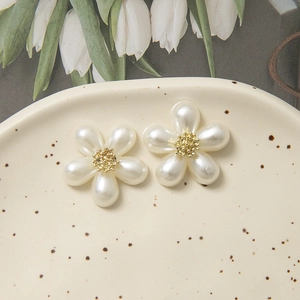 Makro-Detail von Perlglanz-Blumenanhängern mit goldener Mitte für DIY-Schmuckherstellung