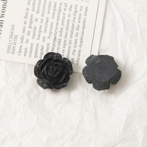 Macro view of matte black rose acrylic flower charms showing petal details and flat back