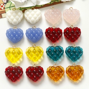Detalle de colgantes de corazón de resina con patrón de rombos y anillas doradas para DIY