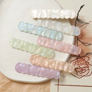 Dettaglio di fermagli per capelli ondulati in acrilico con finitura perlata in sei colori pastello