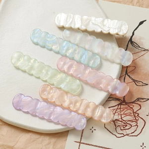 Dettaglio di fermagli per capelli ondulati in acrilico iridato in colori pastello