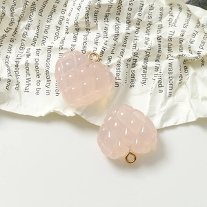 Primer plano de dijes de corazón de resina rosa acolchada con anillos dorados para joyería DIY