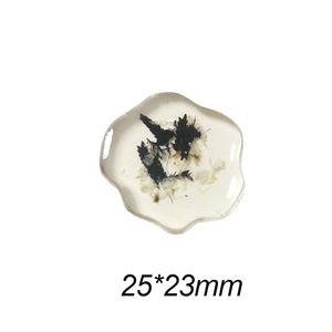 Detail shot of irregular white resin charm with black dried flowers and 25x23mm size label