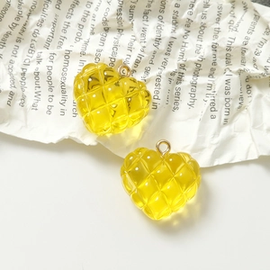 Detalle de dijes de corazón de resina acolchada amarilla con ganchos dorados sobre fondo