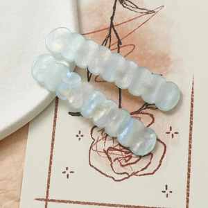 Dettaglio macro di fermagli per capelli in acrilico ondulato con finitura blu iridescente