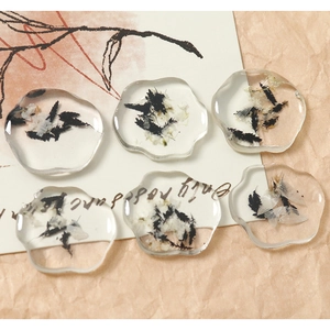 Detailed view of cloud-shaped resin charms with black and white dried flowers for DIY crafts