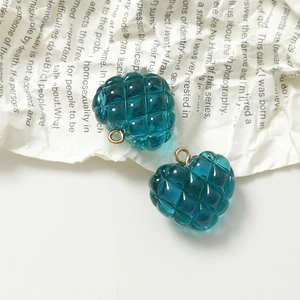 Detalle de dijes de corazón de resina azul pavo real con rombos y aros dorados