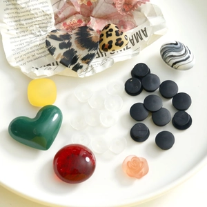 Flat lay of colorful acrylic DIY shoe charms with leopard print hearts on vintage newspaper