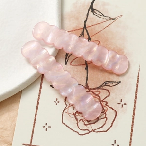Dettaglio di fermagli per capelli rosa iridescenti ondulati con texture marmorizzata