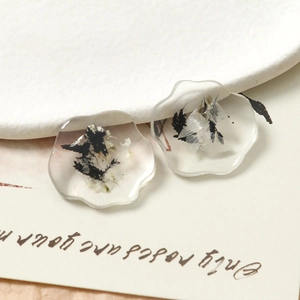 Macro shot of wavy resin charms featuring embedded black and white dried flowers