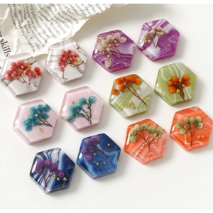 Makro-Detail von sechseckigen Harzanhängern mit Trockenblumen und Goldperlen für DIY