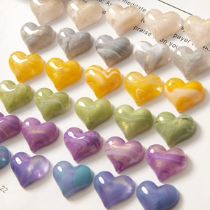 Detail of marble textured resin heart charms with gold glitter for DIY crafts and jewelry