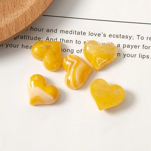 Macro detail of five yellow marble resin heart charms with gold glitter for DIY crafts
