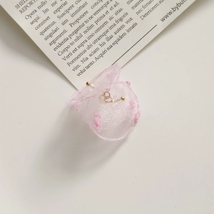 Close-up of pink organza petal earrings with gold beads on a vintage magazine background