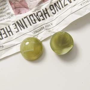 Gros plan de boutons en résine vert olive marbré sur fond de journal rétro chic