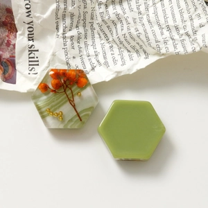 Detail von DIY-Harz-Schmuckstücken mit Marmortextur und floralen Mustern auf Zeitungen