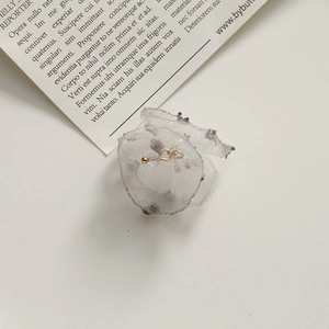 Detail of delicate off-white mesh fabric flower with gold bead center and petal texture