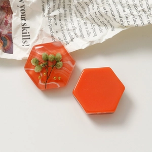 Makro-Detail sechseckiger orangefarbener Harzanhänger mit Trockenblumen für DIY-Schmuck
