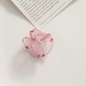 Detailed macro view of a pink sheer mesh flower petal with soft polka dots and beaded core