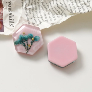 Makroansicht hexagonaler Harz-Anhänger mit blauen Trockenblumen und rosa Marmorstruktur