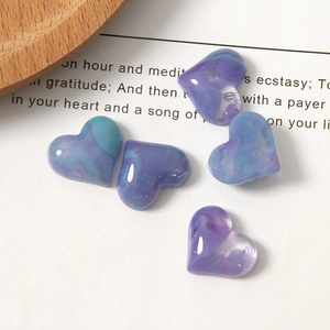 Macro shot of marble textured resin heart charms with a glossy purple and blue gradient finish