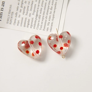 Dettaglio di perline in vetro a forma di cuore con pois rossi per gioielli fai-da-te