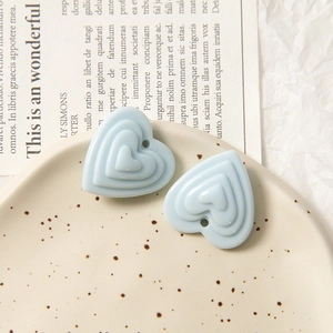 Gros plan détaillé de breloques en forme de cœur bleu clair sur un plateau pour bijoux DIY